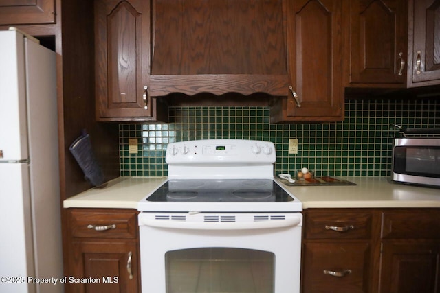 kitchen featuring decorative backsplash, white appliances, light countertops, and extractor fan