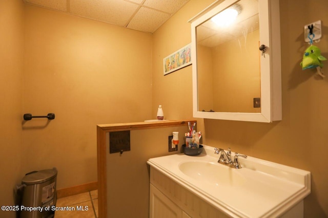 bathroom featuring vanity, tile patterned floors, baseboards, and a drop ceiling