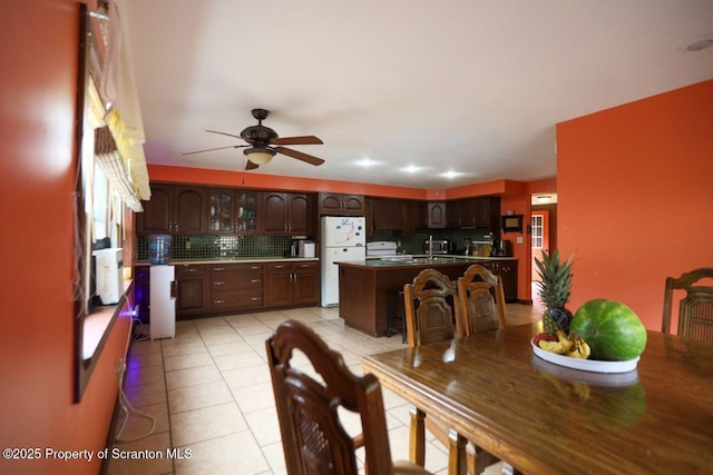 kitchen with backsplash, ceiling fan, light tile patterned floors, freestanding refrigerator, and a kitchen island with sink