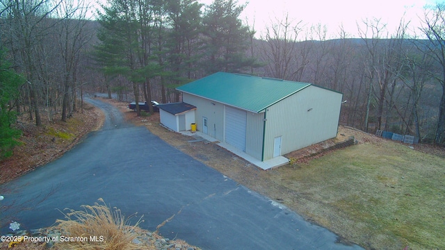 exterior space with aphalt driveway and a view of trees