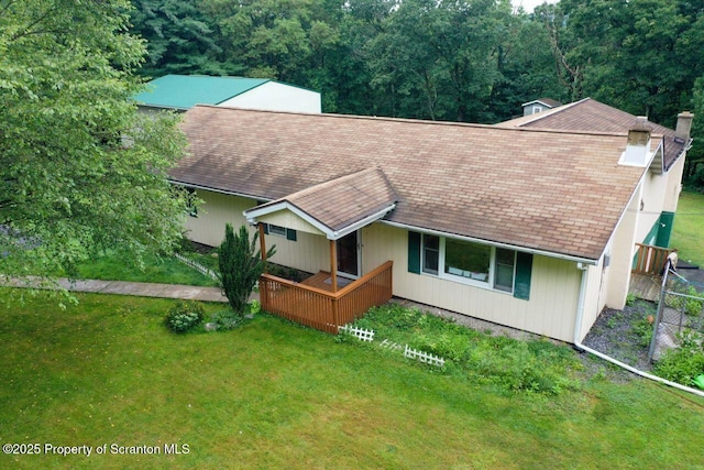 view of front of home featuring a front yard, roof with shingles, and a chimney