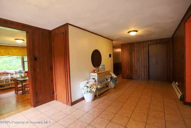 interior space featuring crown molding, light tile patterned flooring, wood walls, and baseboard heating