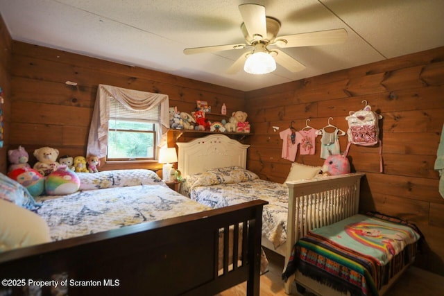 bedroom featuring wooden walls and a ceiling fan