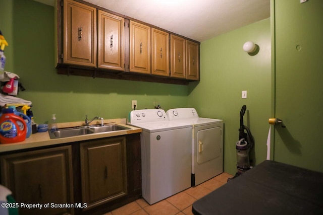 washroom featuring light tile patterned flooring, cabinet space, independent washer and dryer, and a sink