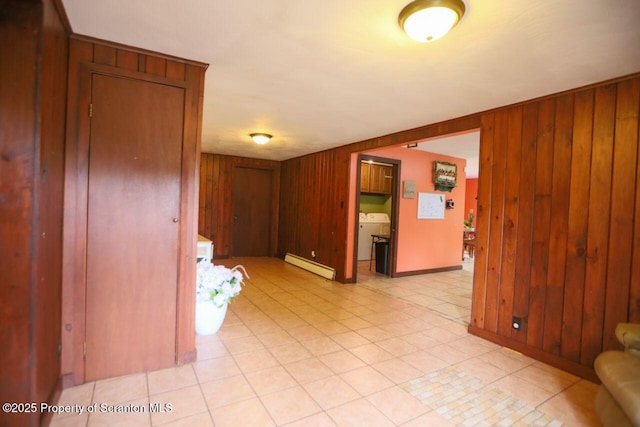 unfurnished room featuring light tile patterned floors, wood walls, washer / clothes dryer, and a baseboard radiator