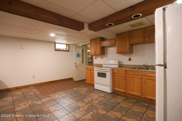 kitchen featuring white appliances, baseboards, a sink, a paneled ceiling, and brown cabinets