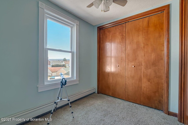 unfurnished bedroom with light carpet, a textured ceiling, baseboard heating, and a closet