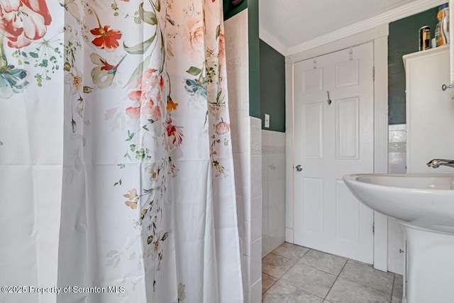 bathroom featuring curtained shower, sink, tile walls, tile patterned flooring, and ornamental molding