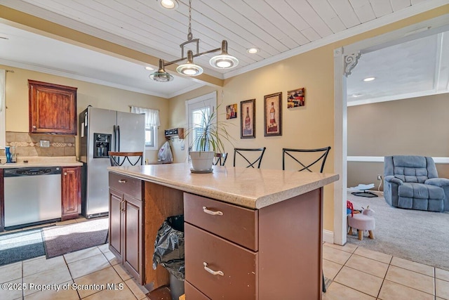 kitchen featuring a breakfast bar, crown molding, light carpet, pendant lighting, and stainless steel appliances