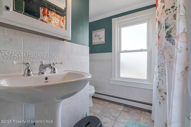 bathroom with toilet, a wealth of natural light, crown molding, and a baseboard heating unit