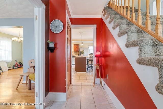 hallway with crown molding, light tile patterned floors, and a chandelier