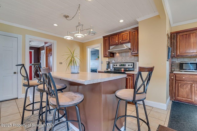 kitchen with light tile patterned floors, crown molding, a breakfast bar area, appliances with stainless steel finishes, and decorative light fixtures