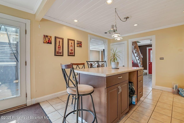 kitchen with crown molding, decorative light fixtures, a center island, and a breakfast bar