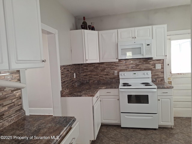 kitchen with dark tile patterned floors, tasteful backsplash, white appliances, and white cabinetry