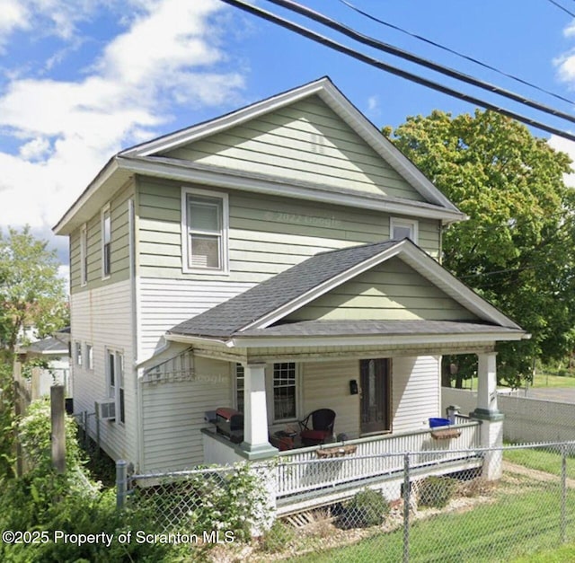 view of front of house featuring covered porch, a shingled roof, fence private yard, and a front lawn