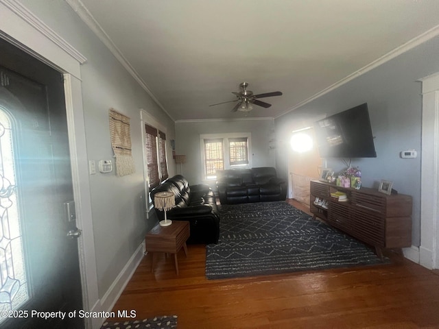 living room featuring a ceiling fan, baseboards, ornamental molding, and wood finished floors