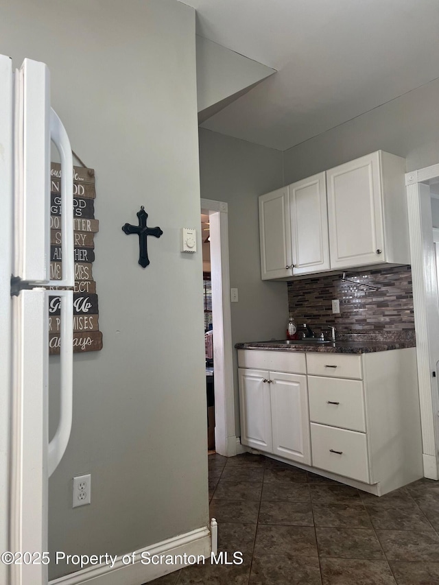 kitchen featuring backsplash, white cabinets, and a sink