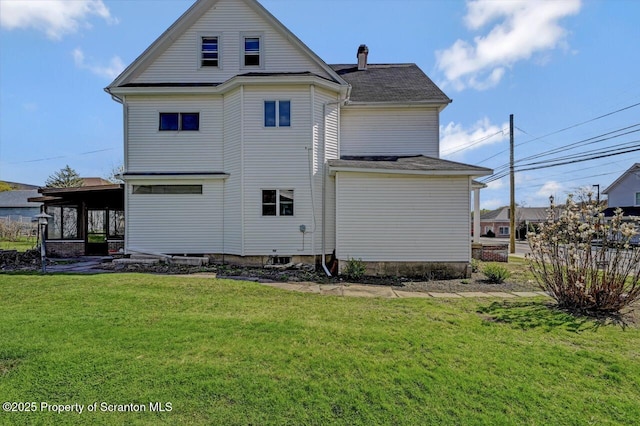 back of house with roof with shingles and a yard
