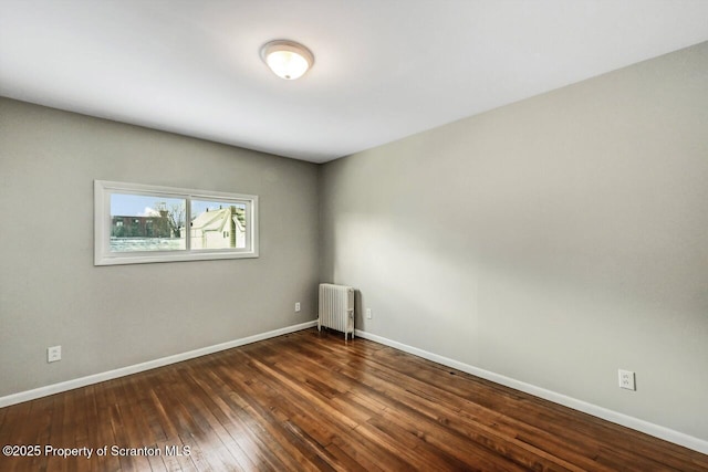 empty room with dark hardwood / wood-style flooring and radiator