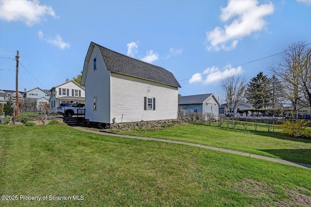 view of side of home featuring a lawn, a shingled roof, and fence