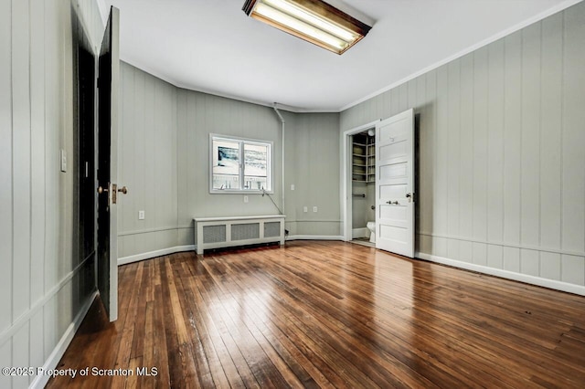 empty room with crown molding, radiator, and hardwood / wood-style flooring