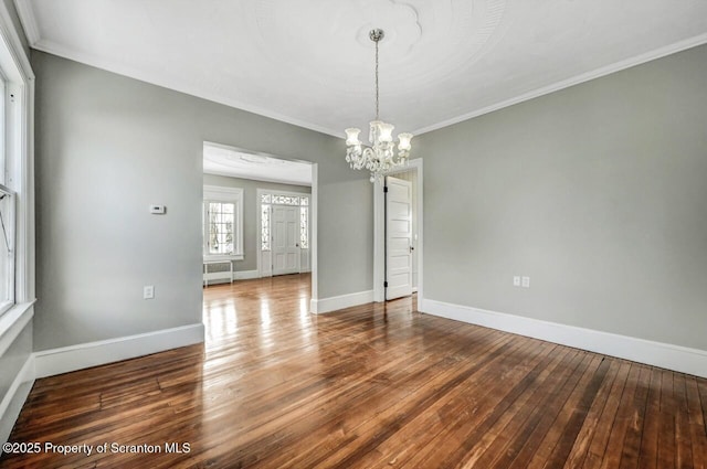 empty room featuring an inviting chandelier, crown molding, radiator heating unit, and wood-type flooring