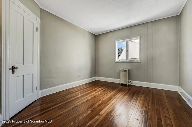 empty room featuring radiator, dark wood-type flooring, and ornamental molding