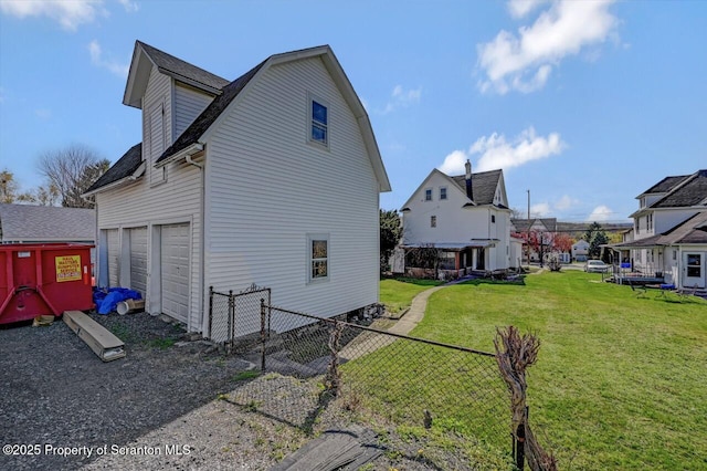 view of side of home featuring a gambrel roof, a lawn, fence, roof with shingles, and a residential view