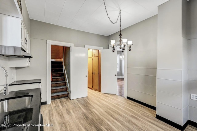 dining space featuring sink, a notable chandelier, and light hardwood / wood-style flooring