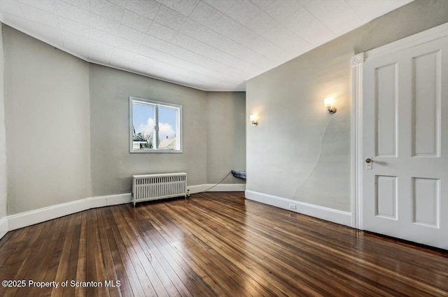 empty room with radiator and dark hardwood / wood-style floors