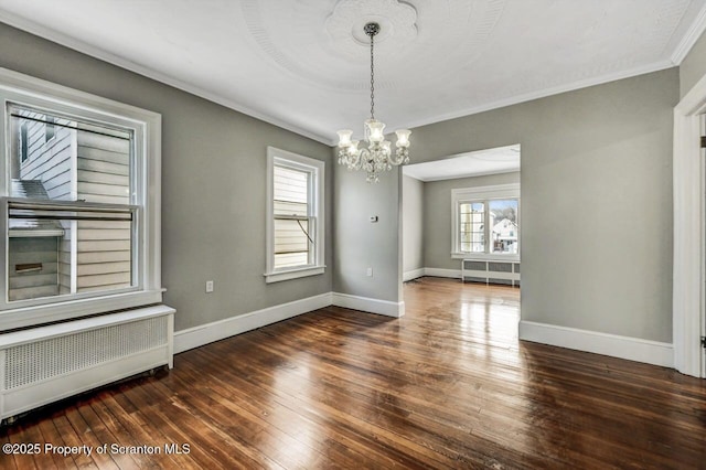 empty room featuring an inviting chandelier, radiator heating unit, dark hardwood / wood-style flooring, and crown molding