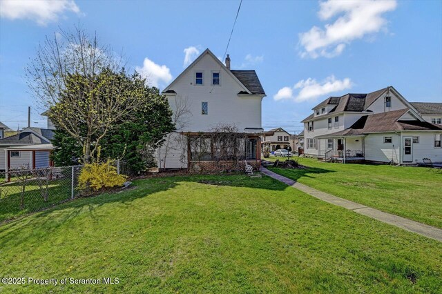 back of property with a chimney, fence, and a yard
