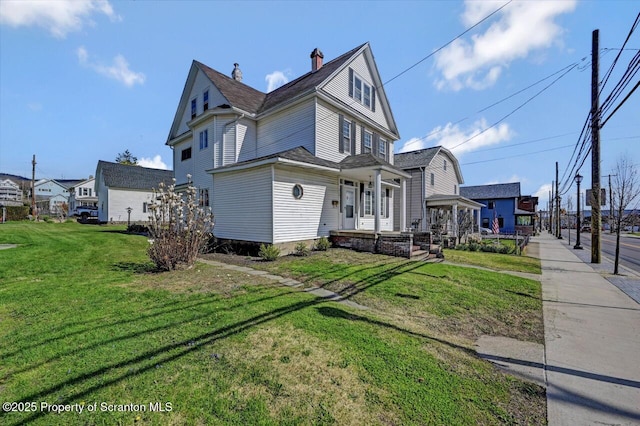view of side of home featuring a yard and covered porch
