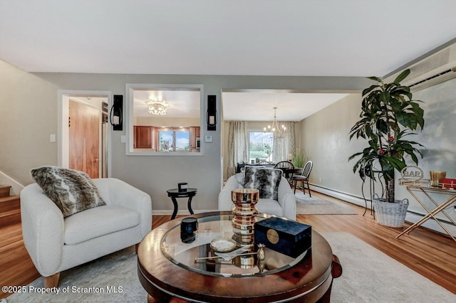 living area with an inviting chandelier, stairs, baseboards, wood finished floors, and a baseboard radiator