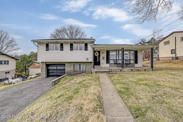 tri-level home featuring a front yard, an attached garage, covered porch, and aphalt driveway