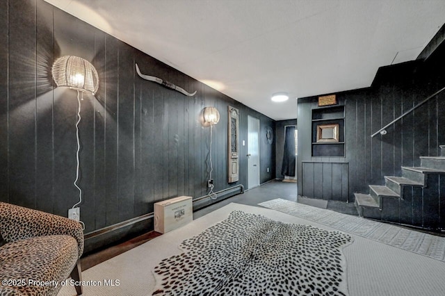 interior space featuring wood walls, a baseboard heating unit, and stairs