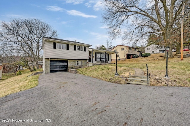 split level home featuring a front lawn, stone siding, a garage, and aphalt driveway