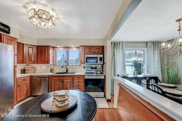 kitchen featuring a sink, decorative backsplash, a notable chandelier, light countertops, and appliances with stainless steel finishes
