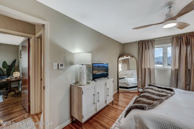 bedroom with a ceiling fan, light wood-style flooring, and baseboards