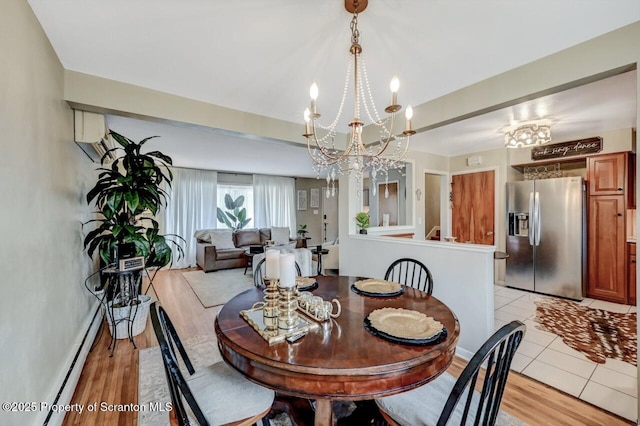 dining area with a baseboard radiator, a chandelier, and light wood-style floors