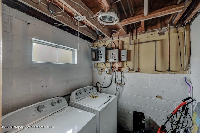 laundry area with electric panel, concrete block wall, washing machine and clothes dryer, and laundry area