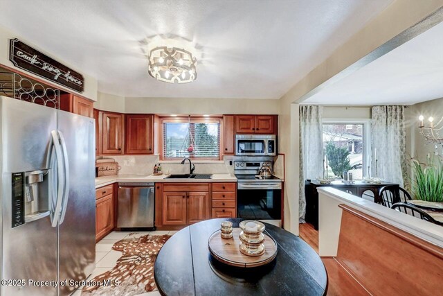 kitchen featuring brown cabinets, decorative backsplash, a sink, stainless steel appliances, and light countertops