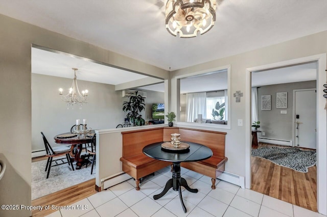 dining space with a baseboard radiator, light wood-type flooring, a notable chandelier, and a baseboard heating unit