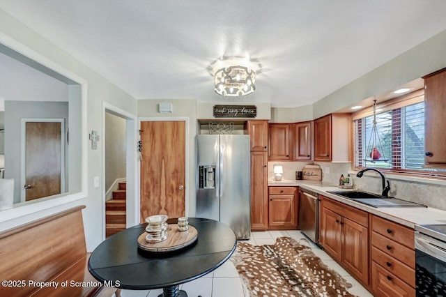 kitchen featuring light tile patterned floors, brown cabinets, decorative backsplash, appliances with stainless steel finishes, and light countertops