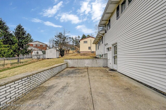 view of patio / terrace with fence, an outdoor structure, a shed, and a residential view