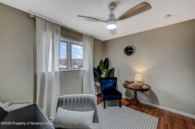 sitting room featuring baseboards, baseboard heating, wood finished floors, and ceiling fan