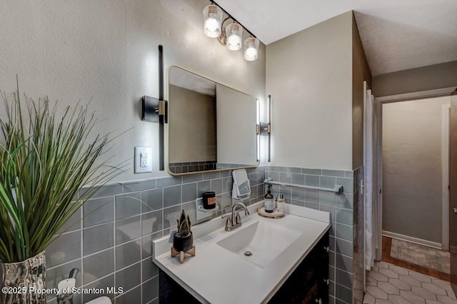 bathroom with tile walls, wainscoting, tile patterned floors, and vanity