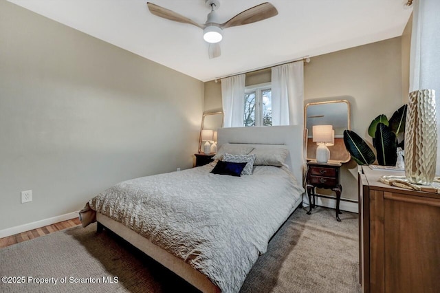 bedroom featuring a baseboard radiator, wood finished floors, a ceiling fan, and baseboards