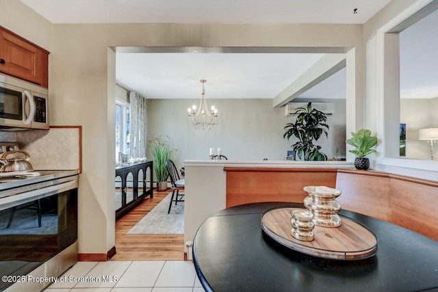 dining space with an inviting chandelier, light tile patterned floors, a wall mounted AC, and baseboards