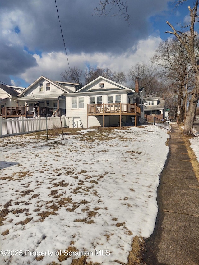 snow covered house with a wooden deck